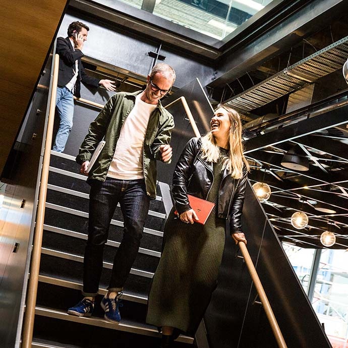 A young man and woman walking down a set of stairs at GridAKL in Auckland